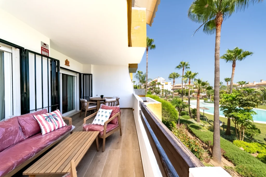 Terrace with an outdoor sofa overlooking palm gardens and a pool